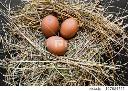 Three Brown Chicken Eggs in Hay Nest Three Brown Chicken Eggs in Hay Nest 127684735