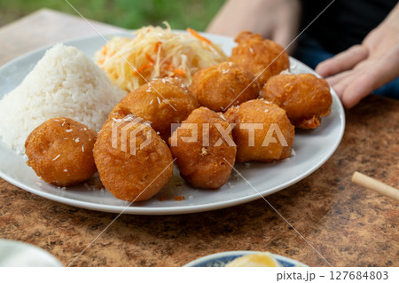 Fried chicken balls with rice and fresh cabbage salad closeup. Deep fried dough balls 127684803