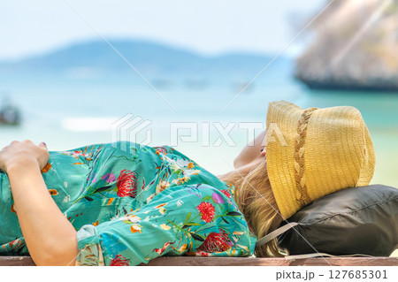 Blonde woman lying on bench and looking to the sea in Thailand Blonde woman lying on bench and looking to the sea in Thailand 127685301
