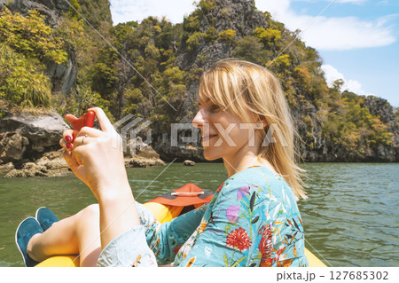 Blonde woman taking picture with cell phone of Thailand landscape 127685302