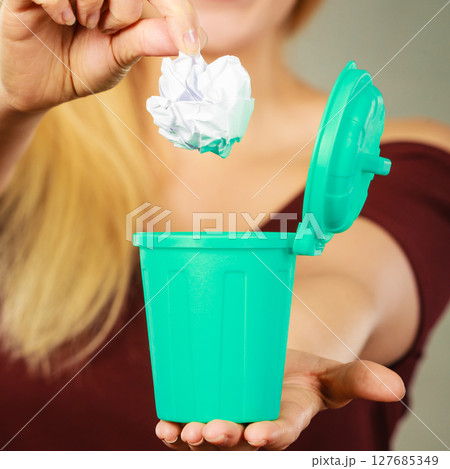 Woman putting paper into small trash can 127685349
