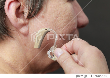 Closeup senior woman using hearing aid 127685350