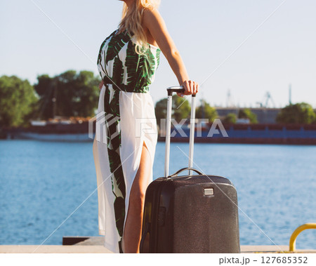 Woman with suitcae on city street 127685352