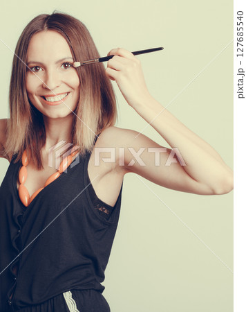 Woman stylist applying eyeshadow with brush. Woman stylist applying eyeshadow with brush. 127685540
