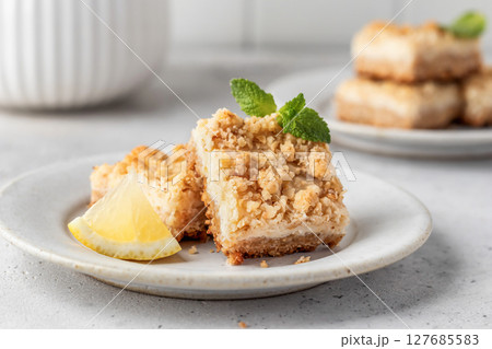Lemon crumble bars served on a plate decorated with mint leaves on light gray background. Oatmeal lemon bars Lemon crumble bars served on a plate decorated with mint leaves on light gray background. Oatmeal lemon bars 127685583
