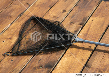 Fishing landing net for fish, fishing tackle on wooden pier 127685730