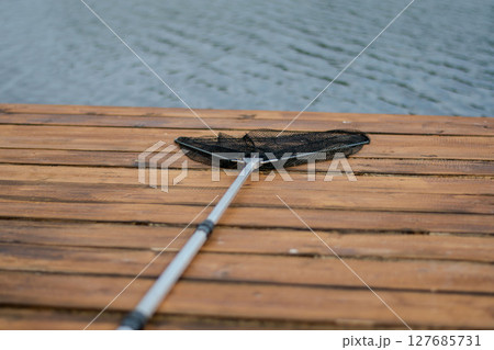 Fishing landing net for fish, fishing tackle on wooden pier Fishing landing net for fish, fishing tackle on wooden pier 127685731