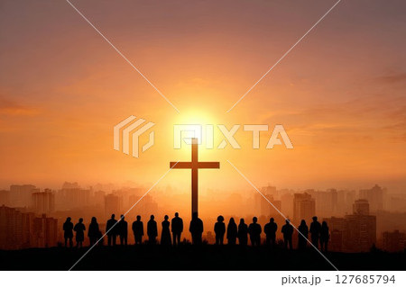 Cross and people at sunset over city. Silhouettes against dramatic urban skyline and glowing sun. 127685794