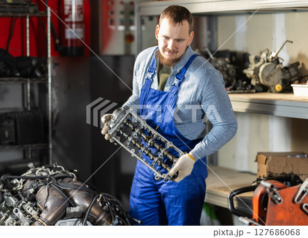 Man professional auto mechanic repairing car engine in garage 127686068