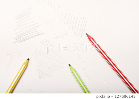 Three colored pencils and an eraser on white paper. Three colored pencils and an eraser on white paper. 127686145