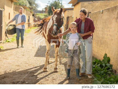 Happy family spending time together at small horse farm 127686172