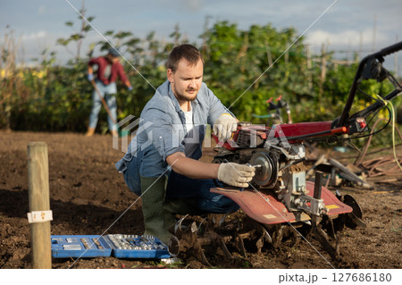 Man repairing cultivator with tools Man repairing cultivator with tools 127686180