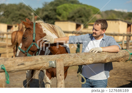 Happy man leading horse by bridle for walk in pasture Happy man leading horse by bridle for walk in pasture 127686189