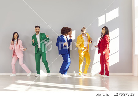Group of young lively people are having fun and dancing, each dressed in stylish colorful suit. 127687315