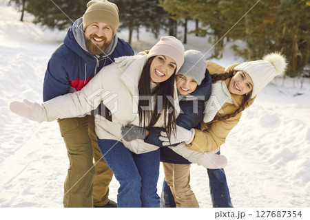 Happy winter snowy outdoor family portrait spending Christmas holiday wearing warm outfit, playful 127687354