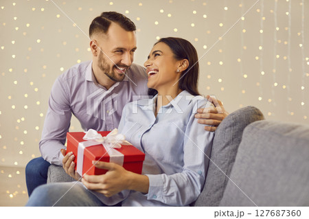 Joyful Couple Sharing Love and Surprises on the Sofa 127687360