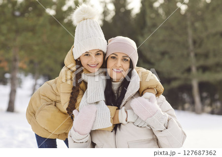 Winter snowy outdoor family portrait, mother, daughter on holiday wearing warm outfit Winter snowy outdoor family portrait, mother, daughter on holiday wearing warm outfit 127687362