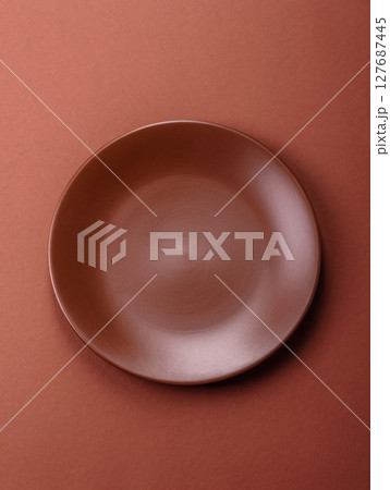 Empty ceramic plate on a monochrome brown background Empty ceramic plate on a monochrome brown background 127687445