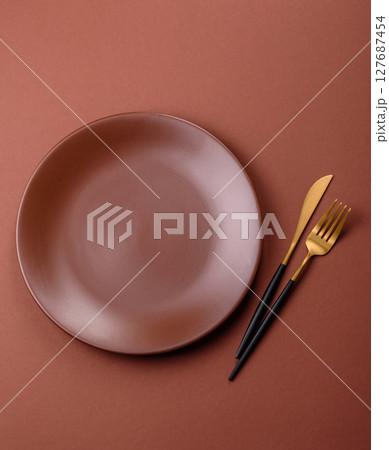 Empty ceramic plate on a monochrome brown background 127687454