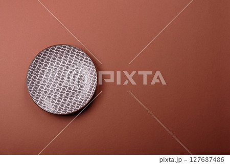 Empty ceramic plate on a monochrome brown background Empty ceramic plate on a monochrome brown background 127687486