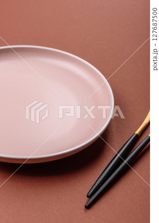 Empty ceramic plate on a monochrome brown background 127687500