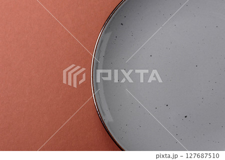 Empty ceramic plate on a monochrome brown background 127687510