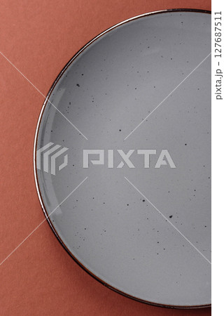 Empty ceramic plate on a monochrome brown background 127687511
