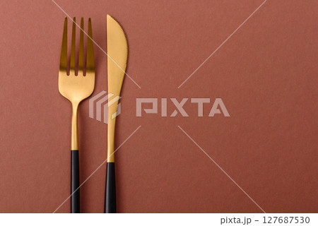 Knife and fork, cutlery on a brown dining table 127687530