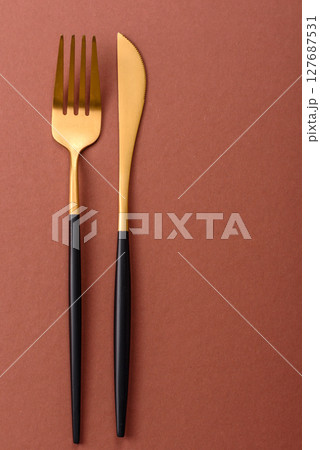 Knife and fork, cutlery on a brown dining table Knife and fork, cutlery on a brown dining table 127687531