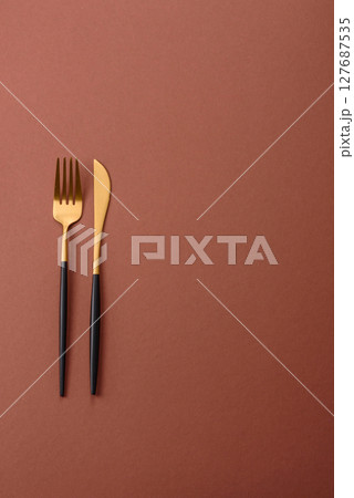 Knife and fork, cutlery on a brown dining table Knife and fork, cutlery on a brown dining table 127687535