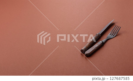 Knife and fork, cutlery on a brown dining table 127687585