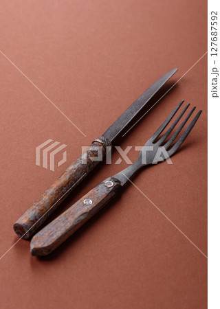Knife and fork, cutlery on a brown dining table Knife and fork, cutlery on a brown dining table 127687592