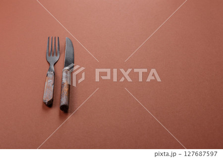 Knife and fork, cutlery on a brown dining table 127687597