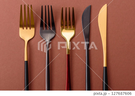 Knife and fork, cutlery on a brown dining table Knife and fork, cutlery on a brown dining table 127687606