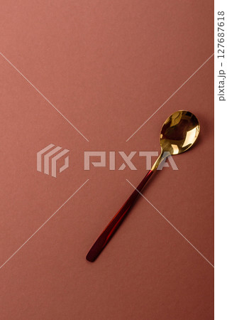 Empty metal spoon on a monochrome brown background 127687618