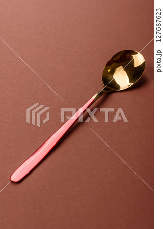 Empty metal spoon on a monochrome brown background Empty metal spoon on a monochrome brown background 127687623