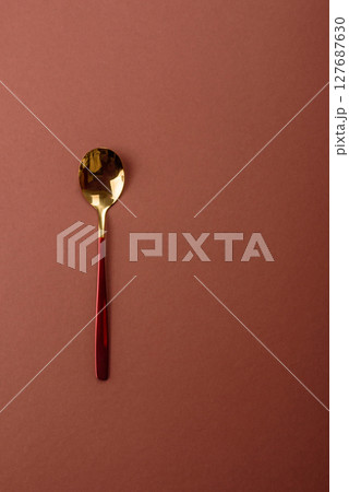 Empty metal spoon on a monochrome brown background 127687630