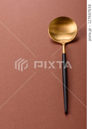 Empty metal spoon on a monochrome brown background Empty metal spoon on a monochrome brown background 127687638