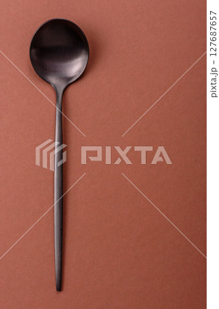 Empty metal spoon on a monochrome brown background 127687657