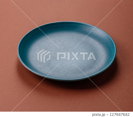 Empty ceramic plate on a monochrome brown background 127687682