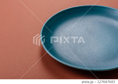 Empty ceramic plate on a monochrome brown background Empty ceramic plate on a monochrome brown background 127687683