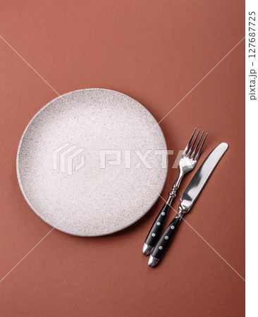 Empty ceramic plate on a monochrome brown background 127687725