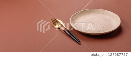 Empty ceramic plate on a monochrome brown background 127687727