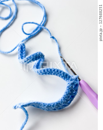 Blue crochet stitch with purple hook on white background 127688251