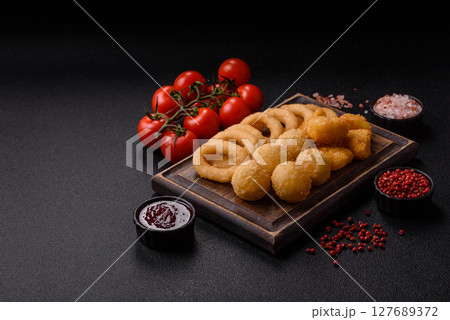 Food, chicken nuggets, onion rings and cheese balls on dark background Food, chicken nuggets, onion rings and cheese balls on dark background 127689372