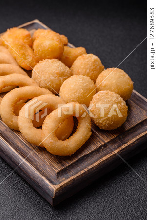 Food, chicken nuggets, onion rings and cheese balls on dark background Food, chicken nuggets, onion rings and cheese balls on dark background 127689383