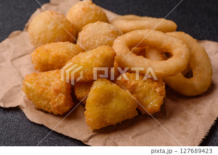Food, chicken nuggets, onion rings and cheese balls on dark background Food, chicken nuggets, onion rings and cheese balls on dark background 127689423