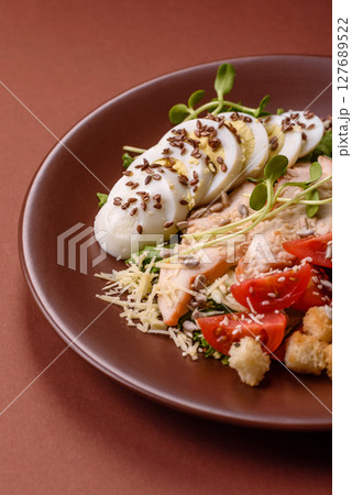 Bowl with caesar salad with chicken, parmesan cheese, tomatoes, croutons, lettuce leaves 127689522