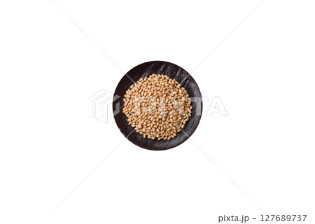 Peeled pine nuts in a bowl on a white background 127689737