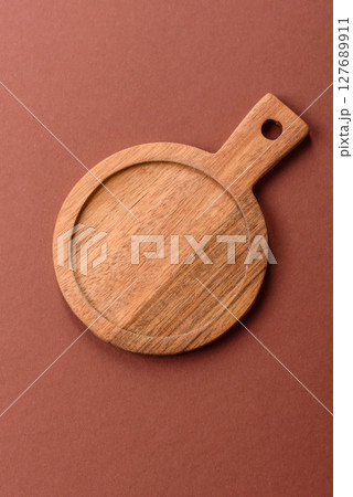 Empty wooden cutting board on a monochrome brown background Empty wooden cutting board on a monochrome brown background 127689911